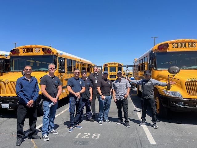Cohort members standing in front of electric school buses